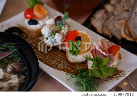 Gourmet Appetizer Platter with Salmon Bruschetta, Cream Cheese Crostini, and Smoked Meat on White Plate Gourmet Appetizer Platter with Salmon Bruschetta, Cream Cheese Crostini, and Smoked Meat on White Plate 139977018