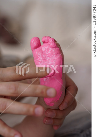 Close up of Toddler Foot Painted in Pink Color with Adult Hands Holding Small Feet Close up of Toddler Foot Painted in Pink Color with Adult Hands Holding Small Feet 139977043