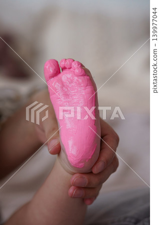 Parent Holding Baby Foot with Pink Paint Impression on Sole in Soft Natural Lighting Parent Holding Baby Foot with Pink Paint Impression on Sole in Soft Natural Lighting 139977044