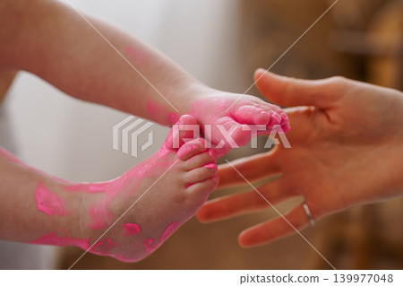 Close Up of Baby Feet Covered in Pink Paint Being Held by Adult Hands Close Up of Baby Feet Covered in Pink Paint Being Held by Adult Hands 139977048