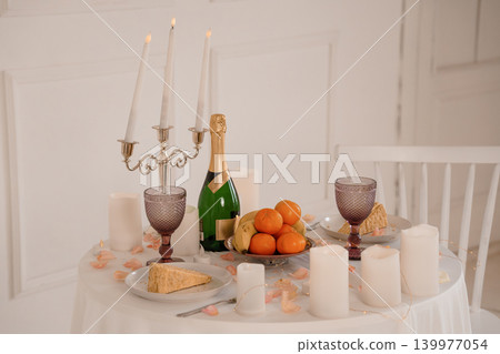 Romantic Dinner Setting with Champagne Bottle, Fruit, and Candelabra on White Tablecloth Romantic Dinner Setting with Champagne Bottle, Fruit, and Candelabra on White Tablecloth 139977054