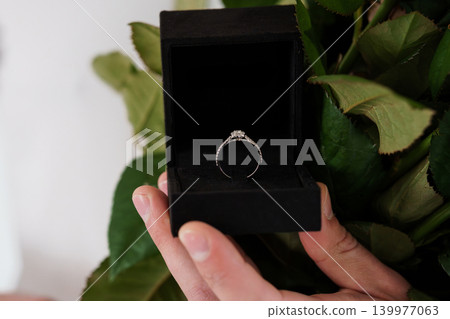 Hand Holding Open Black Velvet Ring Box with Diamond Engagement Ring and Green Leaves Hand Holding Open Black Velvet Ring Box with Diamond Engagement Ring and Green Leaves 139977063