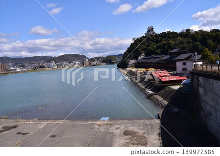 Inuyama City, Aichi Prefecture, Japan. Inuyama Castle and cherry blossoms in full bloom in spring. Kiso River and beautiful blue sky. Many sightseeing boats moored on the riverbank. Inuyama City, Aichi Prefecture, Japan. Inuyama Castle and cherry blossoms in full bloom in spring. Kiso River and beautiful blue sky. Many sightseeing boats moored on the riverbank. 139977385