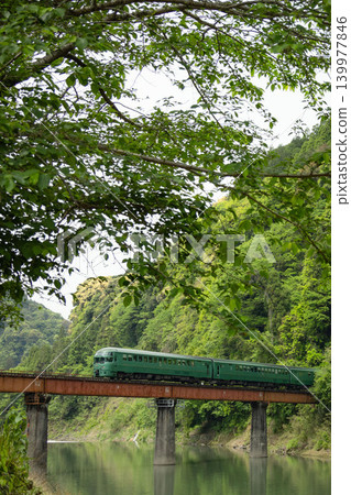 The Yufuin train runs across a railway bridge surrounded by fresh greenery. The Yufuin train runs across a railway bridge surrounded by fresh greenery. 139977846