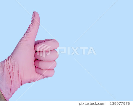 Pink medical glove showing thumbs up gesture for healthcare cosmetology dentistry manicure and diagnostics Pink medical glove showing thumbs up gesture for healthcare cosmetology dentistry manicure and diagnostics 139977976
