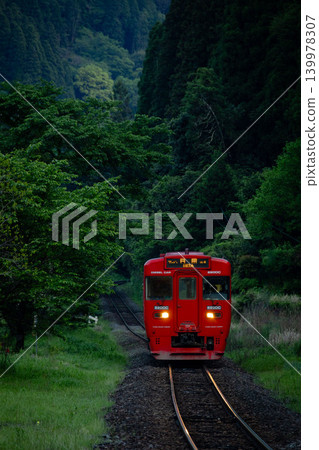 A red local train runs through the mountains at dusk. A red local train runs through the mountains at dusk. 139978307