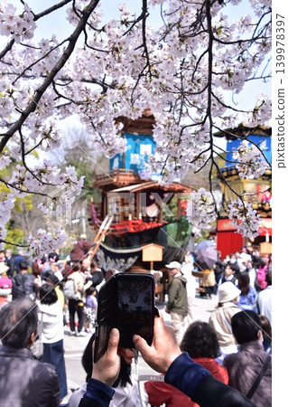 Inuyama City, Aichi Prefecture, Japan: Springtime Inuyama Festival and cherry blossoms in full bloom; floats gathered in front of Inuyama Castle Square; tourists taking photos with their smartphones. Inuyama City, Aichi Prefecture, Japan: Springtime Inuyama Festival and cherry blossoms in full bloom; floats gathered in front of Inuyama Castle Square; tourists taking photos with their smartphones. 139978397