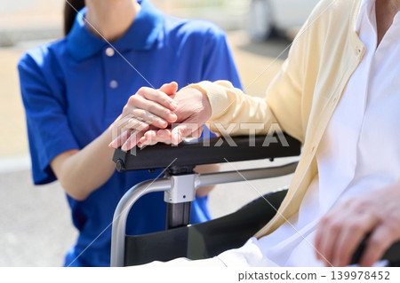 Asian caregiver holds hands with senior citizen Asian caregiver holds hands with senior citizen 139978452