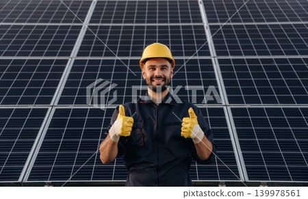 Thumb up gesture. Male solar engineer examining photovoltaic panels at a power station Thumb up gesture. Male solar engineer examining photovoltaic panels at a power station 139978561