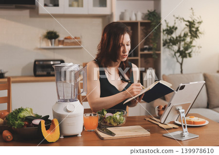 Woman preparing green smoothie in bright kitchen with fresh fruits and vegetables, healthy eating lifestyle moment in natural daylight 139978610