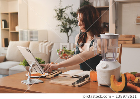 Woman preparing green smoothie in bright kitchen with fresh fruits and vegetables, healthy eating lifestyle moment in natural daylight Woman preparing green smoothie in bright kitchen with fresh fruits and vegetables, healthy eating lifestyle moment in natural daylight 139978611