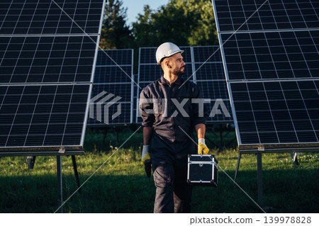 Male solar engineer examining photovoltaic panels at a power station Male solar engineer examining photovoltaic panels at a power station 139978828