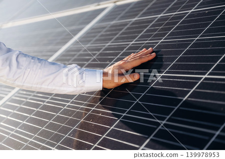 Touching the clean surface. Male solar engineer examining photovoltaic panels at a power station Touching the clean surface. Male solar engineer examining photovoltaic panels at a power station 139978953