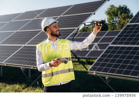 Professional drone is in hand. Male solar engineer examining photovoltaic panels at a power station Professional drone is in hand. Male solar engineer examining photovoltaic panels at a power station 139978956