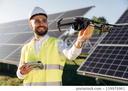 Drone specialist. Male solar engineer examining photovoltaic panels at a power station Drone specialist. Male solar engineer examining photovoltaic panels at a power station 139978961