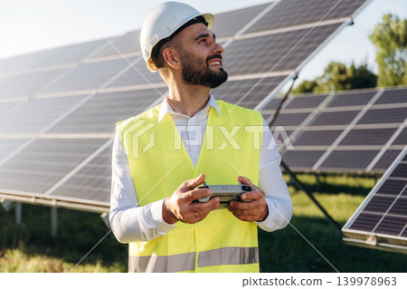Drone specialist. Male solar engineer examining photovoltaic panels at a power station Drone specialist. Male solar engineer examining photovoltaic panels at a power station 139978963