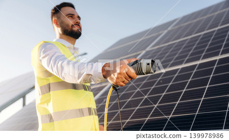 You can charge something by this cable. Male solar engineer examining photovoltaic panels at a power station You can charge something by this cable. Male solar engineer examining photovoltaic panels at a power station 139978986