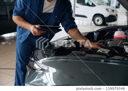 Modern wireless device, tablet in hands. Auto service specialist examining vehicle condition Modern wireless device, tablet in hands. Auto service specialist examining vehicle condition 139979346