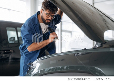 With flashlight in hand. Auto service specialist examining vehicle condition With flashlight in hand. Auto service specialist examining vehicle condition 139979360