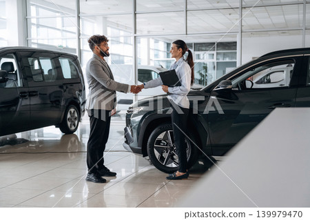 Making a deal. Business consultation between car dealer and buyer in showroom Making a deal. Business consultation between car dealer and buyer in showroom 139979470