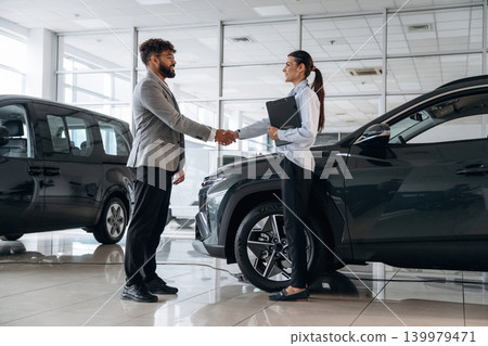 Making a deal. Business consultation between car dealer and buyer in showroom Making a deal. Business consultation between car dealer and buyer in showroom 139979471