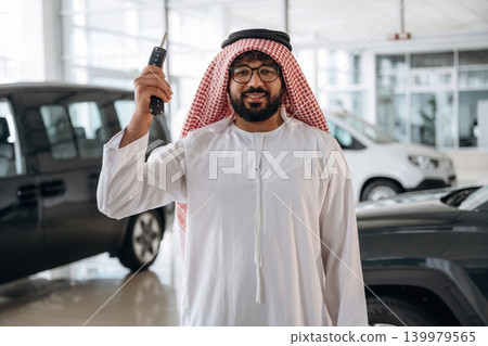 Successful buyer holding car keys in auto showroom Successful buyer holding car keys in auto showroom 139979565