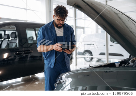 Black digital tablet is in hands. Auto service specialist examining vehicle condition Black digital tablet is in hands. Auto service specialist examining vehicle condition 139979566