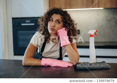 Relaxing, break time. White woman cleaning the kitchen countertop with spray and cloth wearing pink gloves Relaxing, break time. White woman cleaning the kitchen countertop with spray and cloth wearing pink gloves 139979679