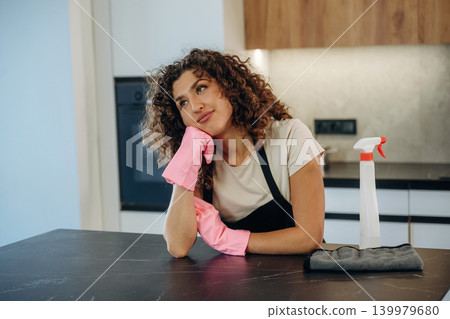Relaxing, break time. White woman cleaning the kitchen countertop with spray and cloth wearing pink gloves Relaxing, break time. White woman cleaning the kitchen countertop with spray and cloth wearing pink gloves 139979680