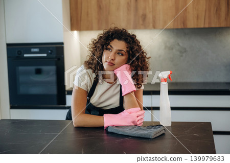 Routine time. White woman cleaning the kitchen countertop with spray and cloth wearing pink gloves Routine time. White woman cleaning the kitchen countertop with spray and cloth wearing pink gloves 139979683