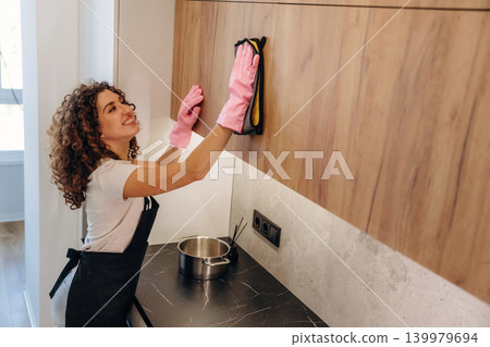 White woman cleaning the kitchen countertop with spray and cloth wearing pink gloves White woman cleaning the kitchen countertop with spray and cloth wearing pink gloves 139979694