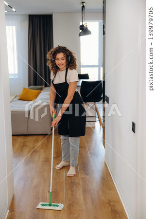 Woman mopping the floor with a cleaning mop in a bright modern home interior Woman mopping the floor with a cleaning mop in a bright modern home interior 139979706