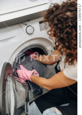 At home. Woman doing laundry with washing machine at home 139979717