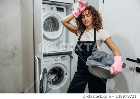 At home. Woman doing laundry with washing machine at home At home. Woman doing laundry with washing machine at home 139979721