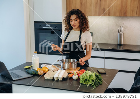 Attractive woman preparing fresh vegetables on the kitchen counter during cooking Attractive woman preparing fresh vegetables on the kitchen counter during cooking 139979751