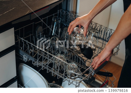 Female loading dishwasher in bright modern kitchen Female loading dishwasher in bright modern kitchen 139979816