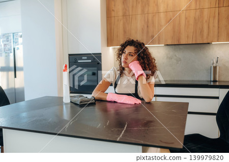 White woman cleaning the kitchen countertop with spray and cloth wearing pink gloves White woman cleaning the kitchen countertop with spray and cloth wearing pink gloves 139979820