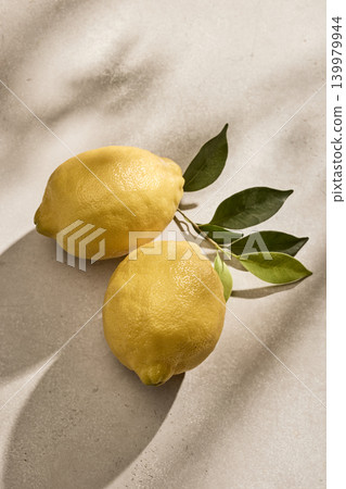 Two Fresh Italian Lemons with Green Leaves on a Kitchen Table. Top View Two Fresh Italian Lemons with Green Leaves on a Kitchen Table. Top View 139979944