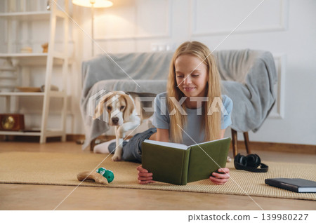 Happy girl is on the floor at home with dog, domestic room Happy girl is on the floor at home with dog, domestic room 139980227