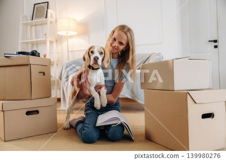Holding animal in hands, embracing. Girl is with her dog on the floor in a cozy living room Holding animal in hands, embracing. Girl is with her dog on the floor in a cozy living room 139980276