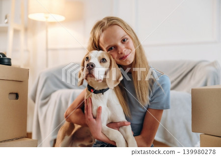 Holding animal in hands, embracing. Girl is with her dog on the floor in a cozy living room Holding animal in hands, embracing. Girl is with her dog on the floor in a cozy living room 139980278