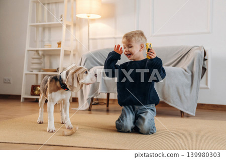 Having fun. Cute little boy playing with dog at home on the floor 139980303