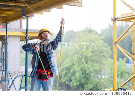 Construction worker operating equipment on building site Construction worker operating equipment on building site 139980412