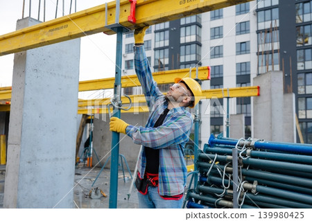 Construction worker adjusting formwork system on building site Construction worker adjusting formwork system on building site 139980425