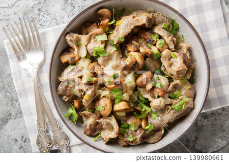 Delicious chicken gizzards cooked with mushrooms and onions close-up in a bowl. Horizontal top view 139980661