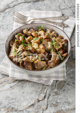 Close-up of stewed chicken gizzards with mushrooms and onions in a bowl. Vertical Close-up of stewed chicken gizzards with mushrooms and onions in a bowl. Vertical 139980669