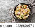 Delicious young potatoes in a creamy mushroom sauce with bacon sprinkled with breadcrumbs and parsley close-up in a frying pan. Horizontal top view 139980671