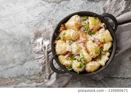 Delicious young potatoes in a creamy mushroom sauce with bacon sprinkled with breadcrumbs and parsley close-up in a frying pan. Horizontal top view Delicious young potatoes in a creamy mushroom sauce with bacon sprinkled with breadcrumbs and parsley close-up in a frying pan. Horizontal top view 139980671