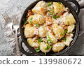Stewed new potatoes in a creamy mushroom sauce with bacon and breadcrumbs close-up in a frying pan. Horizontal top view 139980672