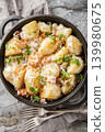 Boiled new potatoes with creamy mushroom sauce and bacon close-up in a frying pan. Vertical top view 139980675